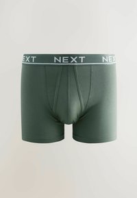Boxer shorts en coton vert avec une ceinture logo "NEXT" blanche et une coupe ajustée. Présente une poche avant et une texture lisse.