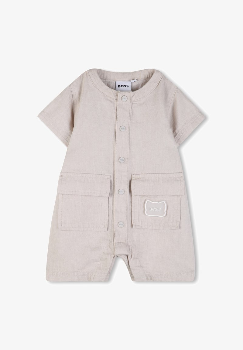 Grenouillère beige à manches courtes pour bébé avec boutons à l'avant, deux poches avant, et un petit écusson en forme de chat avec le texte "BOSS" sur la poche droite.