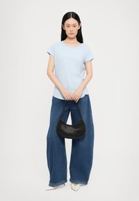 Light blue cotton t-shirt, relaxed fit, paired with high-waisted, wide-leg dark denim jeans. Black woven handbag and pointed white heels.