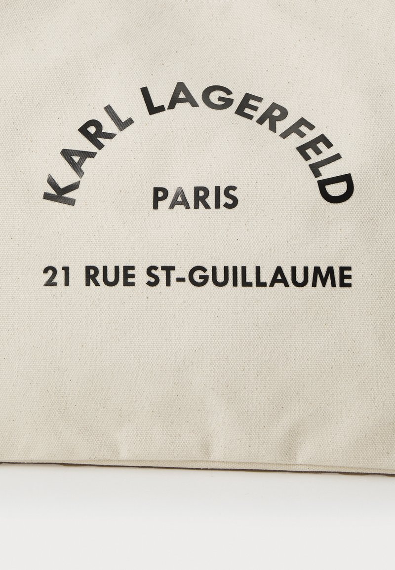 Torebka materiałowa w kolorze beżowym, z czarnym nadrukiem: „KARL LAGERFELD”, „PARYŻ” i „21 RUE ST-GUILLAUME”. Prosty, prostokątny kształt.