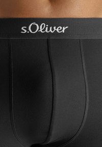 Muška donja rublja u crnoj boji s mekim, elastičnim pojasom s logotipom "s.Oliver". Tkanina ima finu rebrastu teksturu.