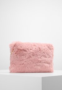 Růžová faux fur taška s měkkou texturou, obdélníkovým tvarem a zlatým kovovým akcentem. Umístěná na bílé ploše.