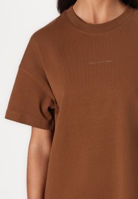 Bruine katoenen T-shirt met ronde hals, korte mouwen en subtiele reliëflogo "Marc O’Polo DENIM" op de borst. Glad textuur.