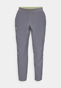 Grå träningsbyxor med en elastisk midja, smalnande design och grön logotypdetalj på vänster sida. Tillverkade av lätt material.