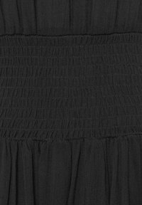 Černá tkanina se smockovaným pásem v pase, s nařasenými sklady níže pro přidanou texturu a objem. Hladký, lehký materiál.