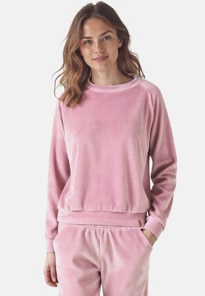 Rosa Velours-Sweatshirt mit lockerer Passform, rundem Ausschnitt und gerippten Bündchen und Saum. Glatte Textur mit sanftem Glanz. Getragen mit passenden rosa Hosen.