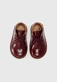 Chaussures d'enfant en cuir bordeaux brillant, avec des bouts ronds, un système de laçage, des détails festonnés et une semelle intérieure en cuir tan.