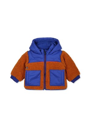 Veste matelassée avec un dessus en nylon bleu et un bas en polaire orange duveteux, comportant deux poches avant et une capuche. Tissu texturé, manches courtes.