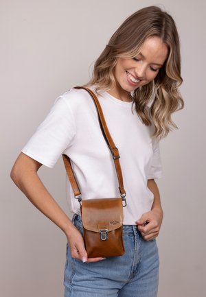 Bolso crossbody de cuero marrón con un acabado texturizado, cierre magnético y correa ajustable. Forma rectangular compacta.