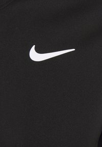 Tela atlética negra con un logo de Swoosh blanco de Nike. El material es suave, con un ligero brillo y un diseño ajustado.