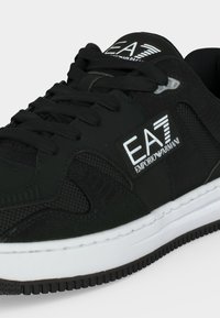 Μαύρο sneaker EA7 Emporio Armani με μαύρα κορδόνια, λευκό λογότυπο στο πλάι και λευκή λαστιχένια σόλα με υφή.