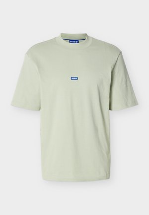Lichtgroen T-shirt met korte mouwen, geribde ronde hals en een klein blauw "HUGO" logo badge in het midden van de borst.