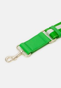 Zelený kožený pásek se zlatými detaily, který obsahuje širokou tkanou část se zelenými a bílými pruhy a plochý polstrovaný konektor.