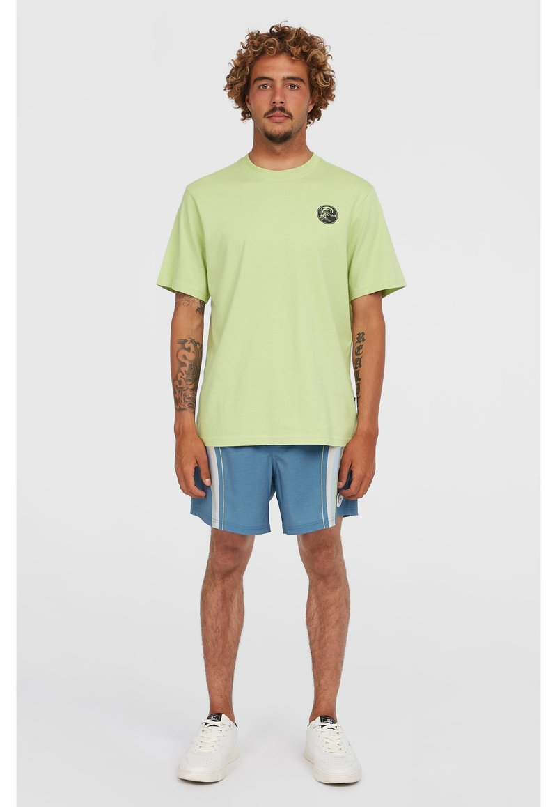Camiseta de manga corta verde claro con cuello redondo y un logo circular. Combinada con pantalones cortos azules con rayas blancas y bolsillos laterales.