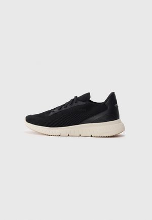 Black knit athletic sneaker with white textured sole and laces, side embossed with "BOSS" branding, shown in profile on white background.