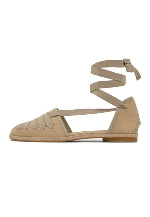 Zapato tipo espadrilla plano beige con puntera cerrada, tejido de tela, correas para atar al tobillo y suela baja de goma.