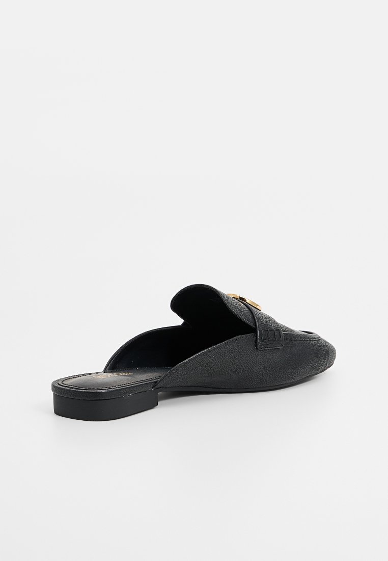 Zwarte instap schoenen met een textuurleer bovenkant, voorzien van een kleine gouden accent, platte zool en een afgeronde neusdesign.
