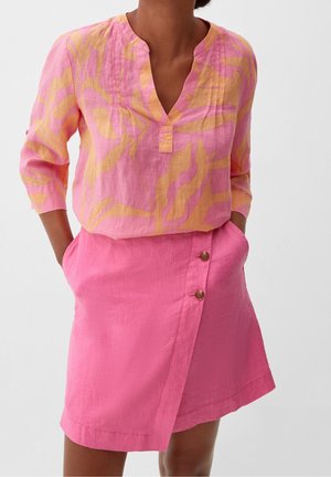 Haut en lin à motifs roses et jaunes avec un décolleté en V et des manches trois-quarts, associé à une jupe portefeuille rose avec des boutons.