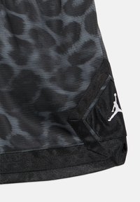 Mustad spordipüksid peene leopardimustriga, tekstuurse kangaga ja valge logoga ääres. Disaini rõhutavad tugevdatud õmblused.