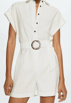 Combinaison blanche sans manches avec un devant à boutons et une large ceinture ornée d'une boucle ronde en écaille de tortue, portée par une personne debout.