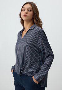 Blusa a righe blu navy con righe rosa, design con colletto, maniche lunghe e dettaglio anteriore annodato. Tessuto morbido con una vestibilità comoda.