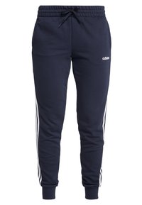 Marina blå sweatpants i mjukt tyg med dragsko i midjan, prydda med vita sidosträck och en adidas-logotyp på vänster ben.