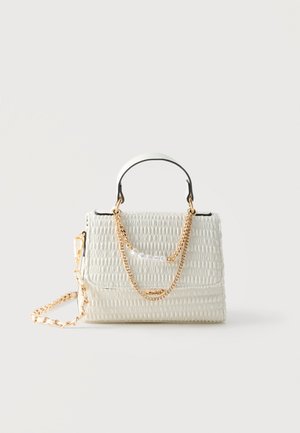 White textured handbag with black trim, gold chain and pearl detail, short handle, and detachable gold chain shoulder strap.