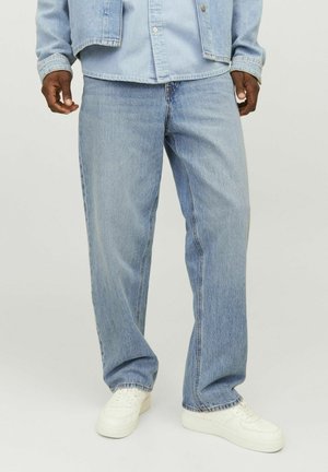 Light blue denim jeans with a relaxed fit, straight leg, and subtle fading, paired with white sneakers for contrast.