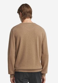 Beige Pullover, weiche Textur, lange Ärmel, Rundhalsausschnitt, lockere Passform, gerippter Saum und Bündchen, schlichtes Design, keine sichtbaren Muster oder Beschläge.