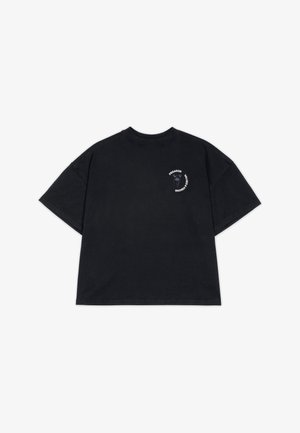 Camiseta de algodón negra de corte oversized con mangas cortas. Presenta un pequeño estampado gráfico en el lado izquierdo del pecho en blanco y azul.