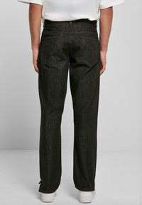 Mustad denim teksased otse lõikega, tagakotidega ja tekstuuriga viimistlusega. Koos valgete tossudega.