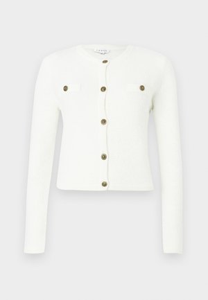 Bijela kardigan s dugim rukavima, okruglim izrezom i krojenjem iznad struka. Ima zlatne gumbe i dva mala prednja džepa. Mekana tekstura.