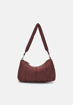 Petit sac à épaule matelassé marron avec une sangle courte et large et une fermeture éclair sur un fond uni.