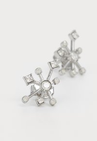 Srebrne naušnice u obliku pahulje snijega s prozirnim rhinestones različitih veličina postavljenim unutar geometrijskog dizajna.