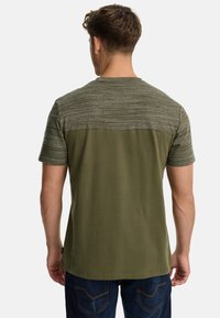 T-shirt w kolorze oliwkowym z teksturowaną, wzorzystą górną częścią i gładką dolną częścią, krótkimi rękawami oraz okrągłym dekoltem.