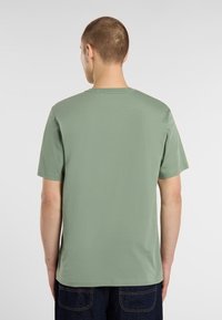 Mentolově zelené tričko vyrobené z měkké bavlny, s krátkým rukávem a klasickým kulatým výstřihem. Žádné grafiky ani vzory nejsou přítomny.