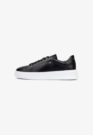 Zapatilla deportiva de cuero negro con textura suave, suela de goma blanca, seis ojales y un pequeño logo en el costado.