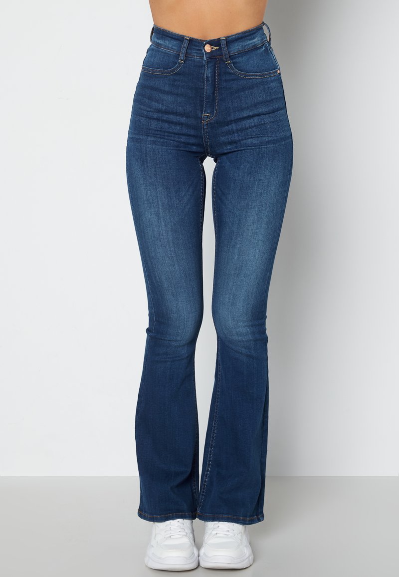 Hoge taille, blauwe jeans met een uitlopende onderkant, gemaakt van denim met een lichte vervaging. Bevat gouden accenten op de knoop en zakken.