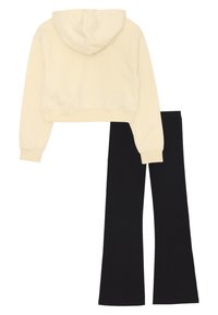 Felpa beige corta con maniche lunghe abbinata a pantaloni neri a vita alta e a zampa, esposta piatta su sfondo bianco.