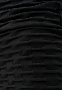 Tissu noir texturé avec des sections relevées superposées. Le design présente des lignes ondulées et une apparence douce et extensible.