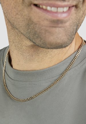 Halskette mit goldfarbener Kette und ineinandergreifenden Gliedern, die auf einem grauen Shirt mit Rundhalsausschnitt liegt und eine glatte Textur sowie glänzende Oberfläche zeigt.