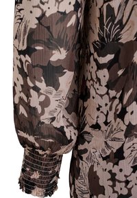 Blouse à motifs floraux marron et beige avec un tissu texturé, manches bouffantes longues et poignets froncés.