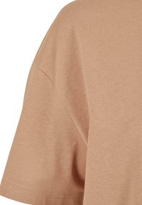 Béžové bavlněné tričko s krátkým rukávem, kulatým výstřihem a měkkou texturou. Má regular fit a čisté stehové detaily.