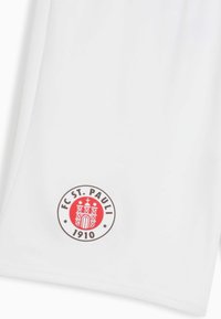 Vita idrottsshorts med en cirkulär FC St. Pauli-logotyp i röd och brun, som visar ett slottsdesign och text med året 1910.