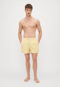Gelbe und weiße gestreifte Bade Shorts, mit einem elastischen Bund und Kordelzug, Seitentaschen und einem lockeren Sitz.