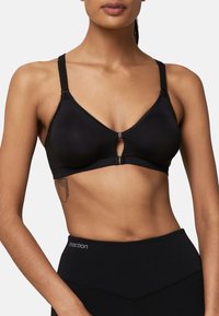 Black, wireless bra with a triangular shape, adjustable straps, and a front clasp. Smooth texture and minimal design, suited for comfort.