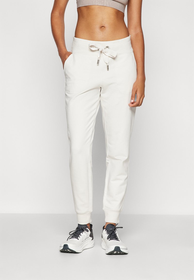 Hvite joggebukser med snøring i livet, to sidelommer og avsmalnende mansjetter. Kombinert med svart-hvite treningssko.