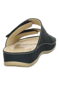 Sandal noir avec trois sangles ajustables, semelle beige et semelle intérieure texturée. Présente un détail cousu le long du bord et un talon courbé.
