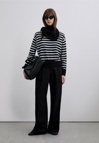 Svart- och vitrandig tröja, långa svarta byxor och en svart väska. Accessoarer inkluderar en svart halsduk och kantiga solglasögon. Släta texturer.