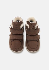 Bruine suède schoenen met een zachte bontvoering, voorzien van een berengezicht ontwerp aan de voorkant en twee verstelbare klittenbandriemen. Rubberen zool.